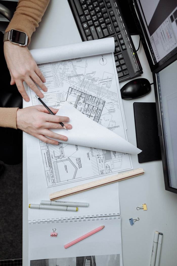 High-angle view of an architect reviewing construction drawings on a desk in an office.